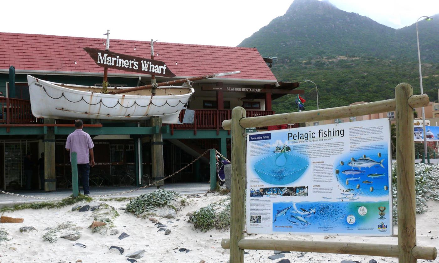 The Mariner's Wharf building on Hout Bay harbour, a lifeboat mounted on its balcony and the mountain behind.