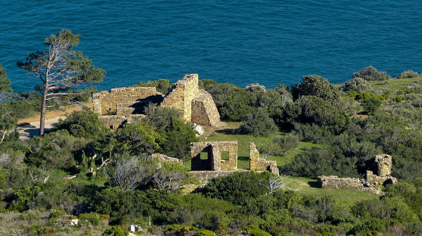 The stone ruins of East Fort on the slope above Hout Bay, with the sea directly beyond.