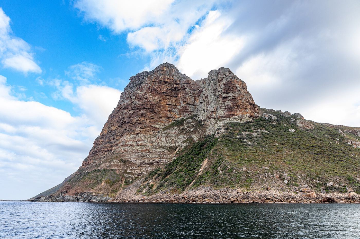 The Sentinel rising steeply out of the sea at the mouth of Hout Bay, photographed from the water.